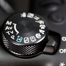 Cover of our Camera Basics Course book featuring a camera mode dial
